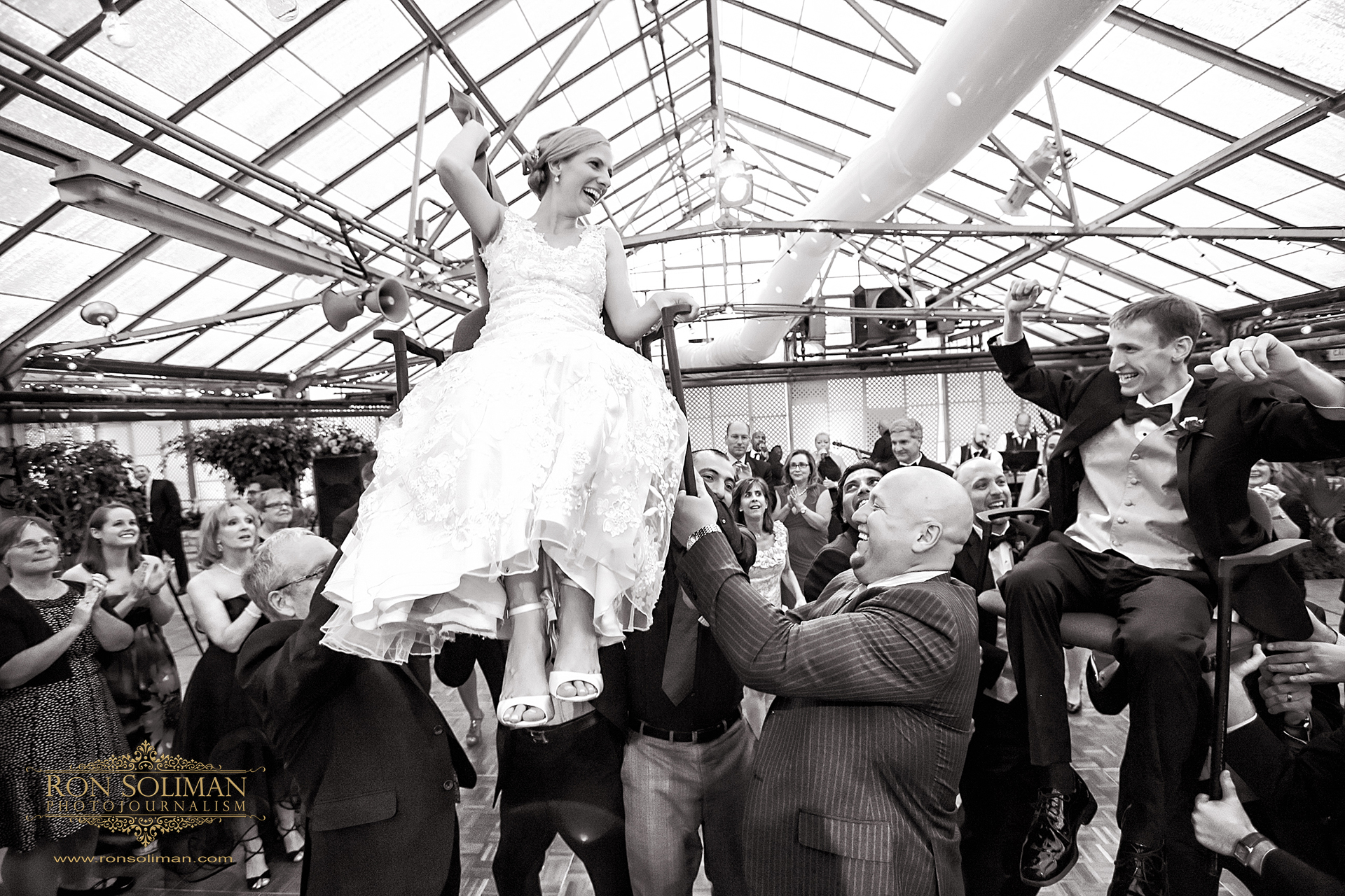 bride and groom being carried on chairs